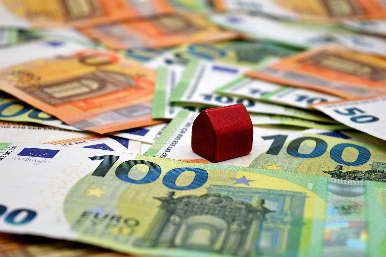 Rotes Spielzeughaus auf ausgebreiteten Hundert-Euro-Scheinen