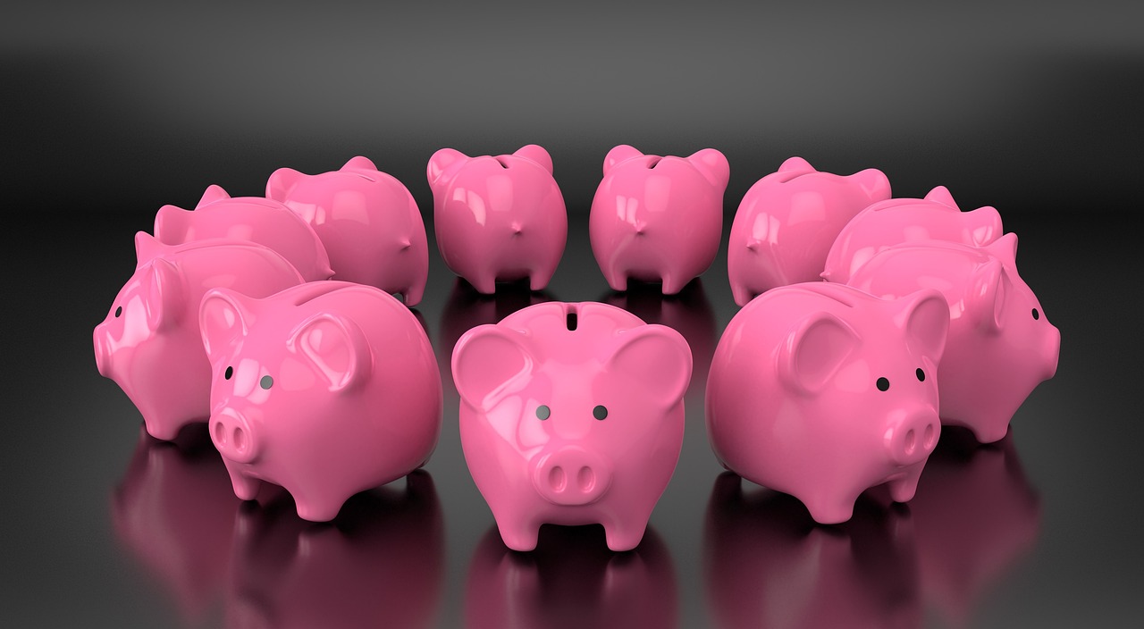 Fünf rosa Sparschweine nebeneinander vor dunklem Hintergrund